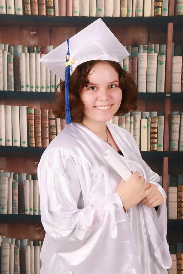 Teen in graduation gown with cap and holding diploma