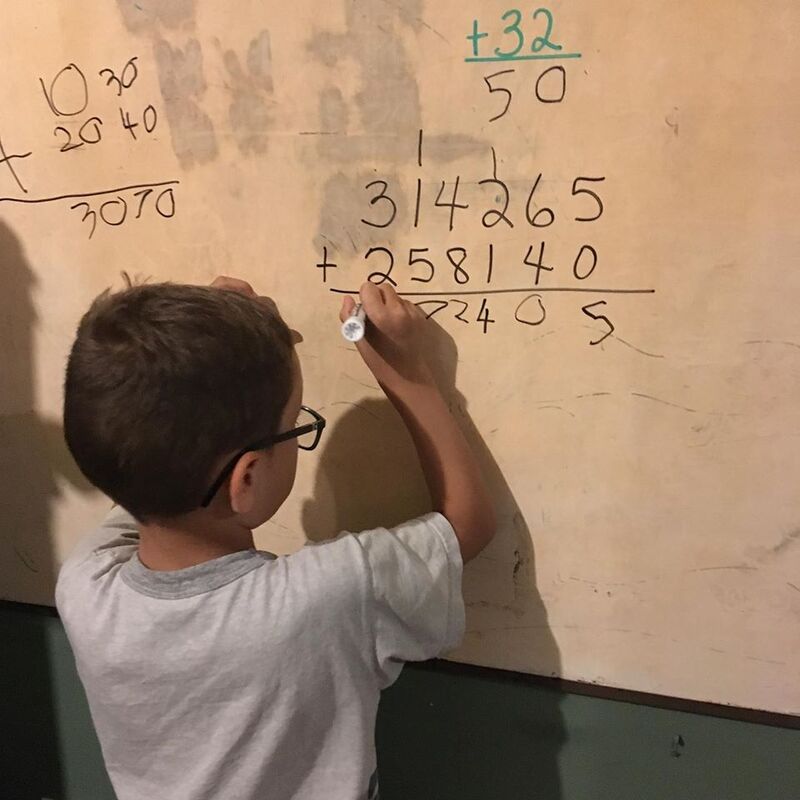 Photo of young boy working on a big addition problem.